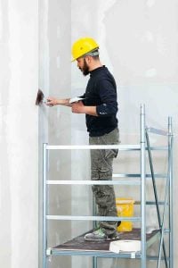 worker plastering gypsum board wall.