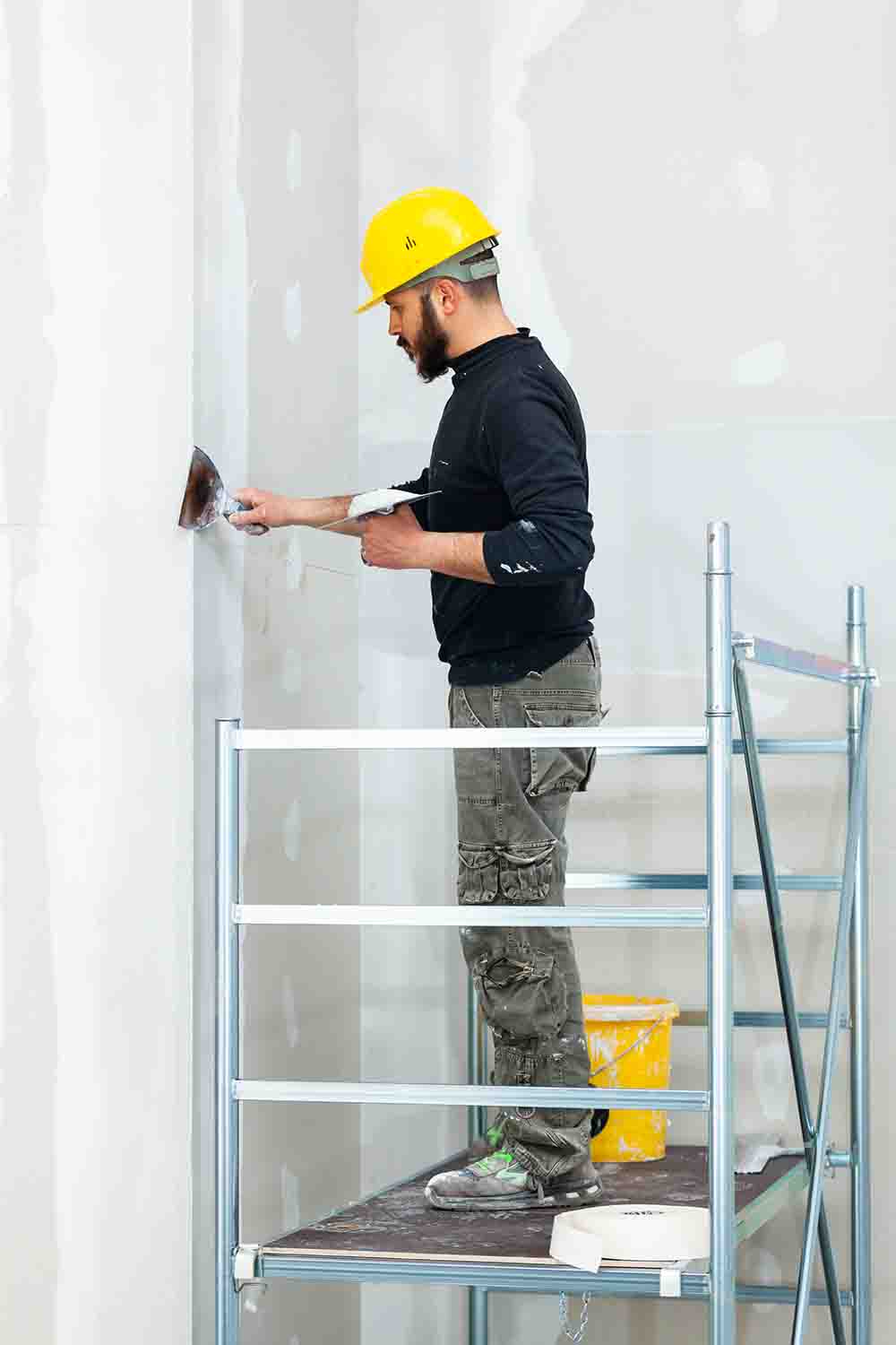 worker plastering gypsum board wall.